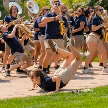 marching band outdoor show, student doing the worm in front 